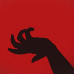 Der Schatten einer verkrampften Hand vor einer roten Wand