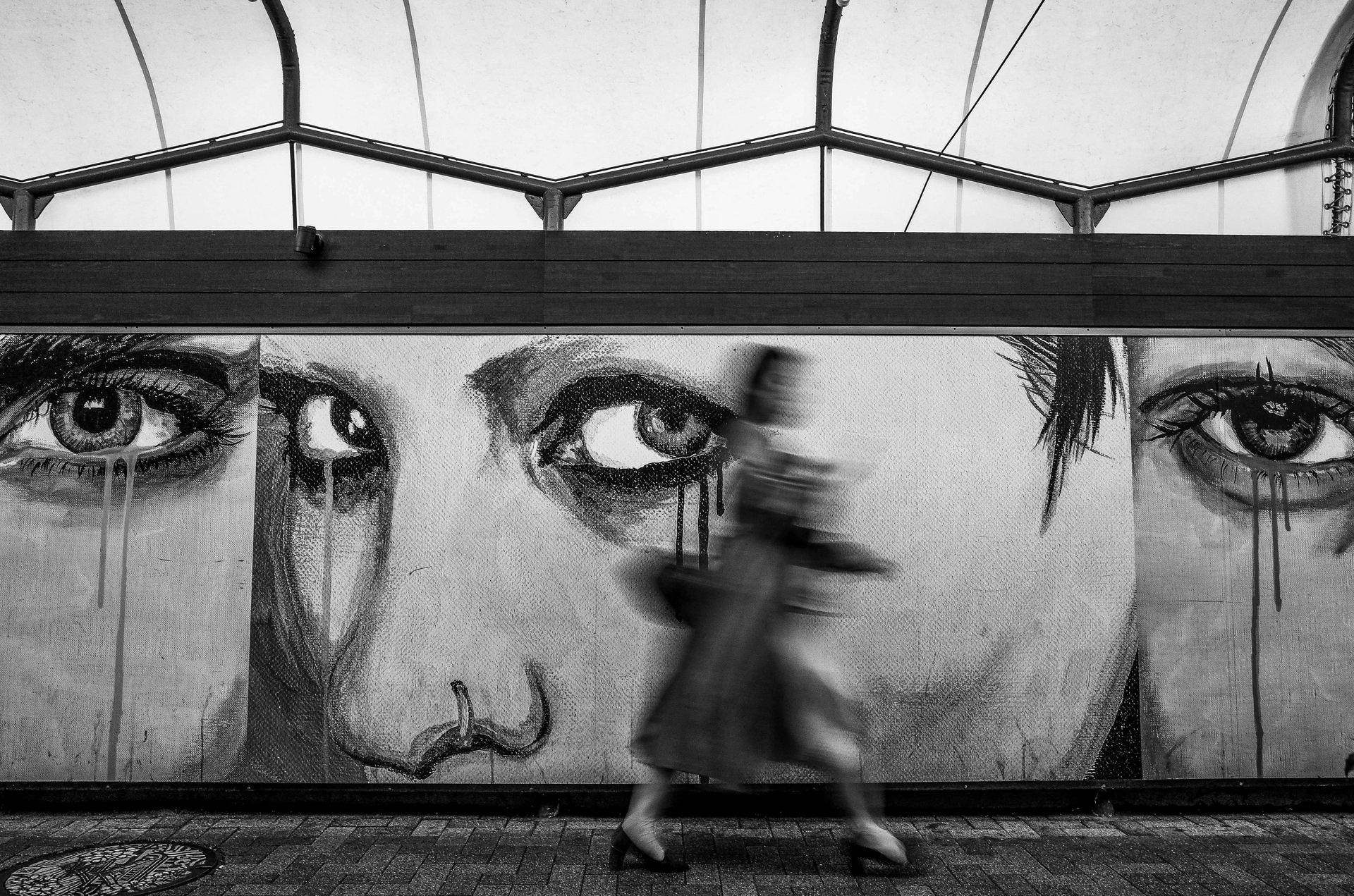 Eine Wand mit Street Art, eine Frau läuft vorbei, sie ist verschwommen fotografiert
