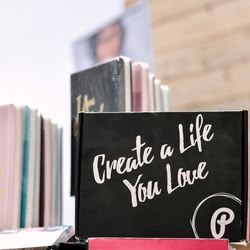 Ein Notizbuch mit der Aufschrift "Create a Life You Love" steht vor anderen Notizbüchern