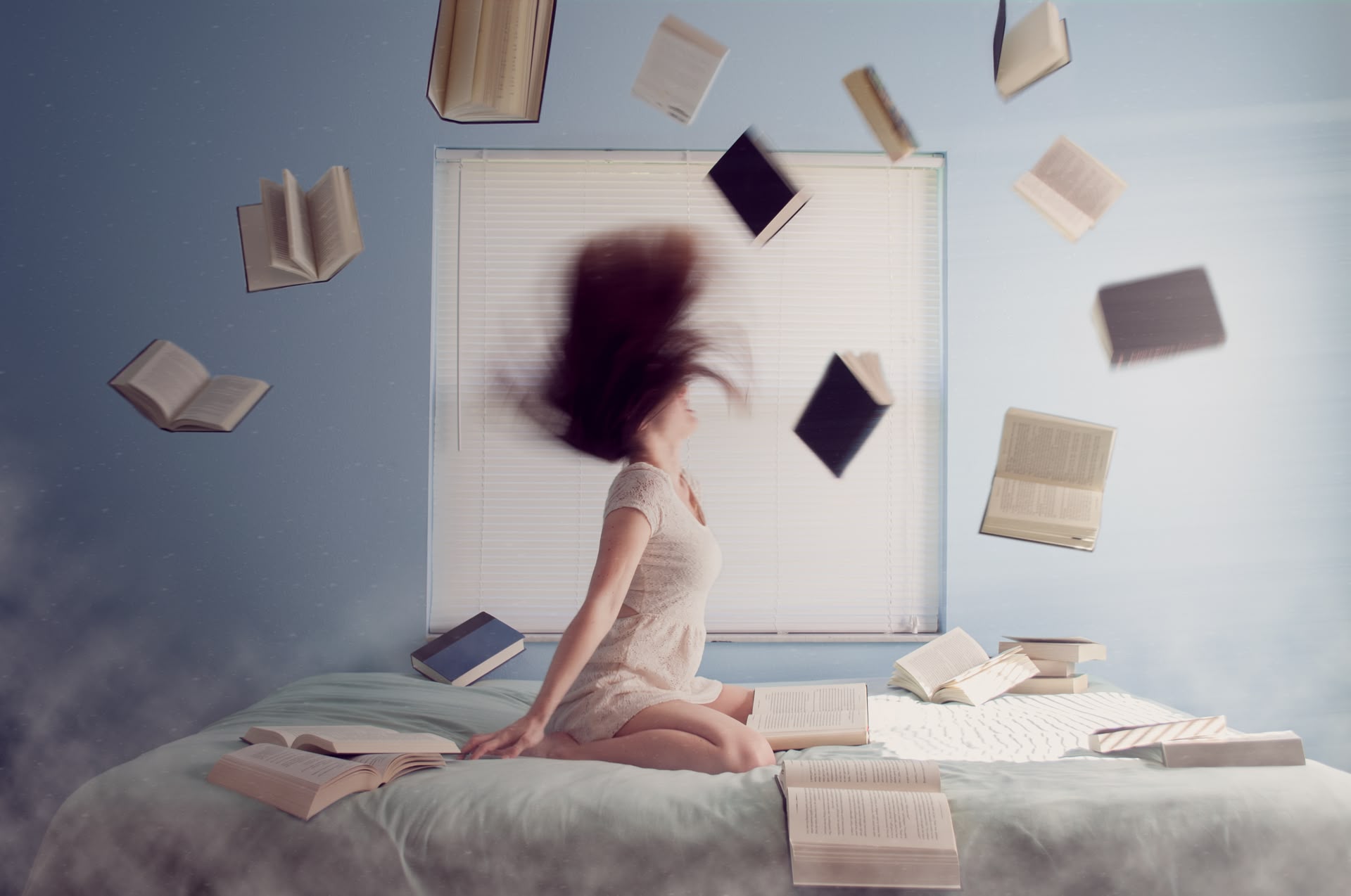 Eine Frau sitzt auf einem Bett, um sie herum fliegen Bücher