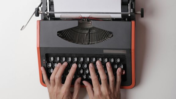 2 Hände auf der Tastatur einer mechanischen Schreibmaschine