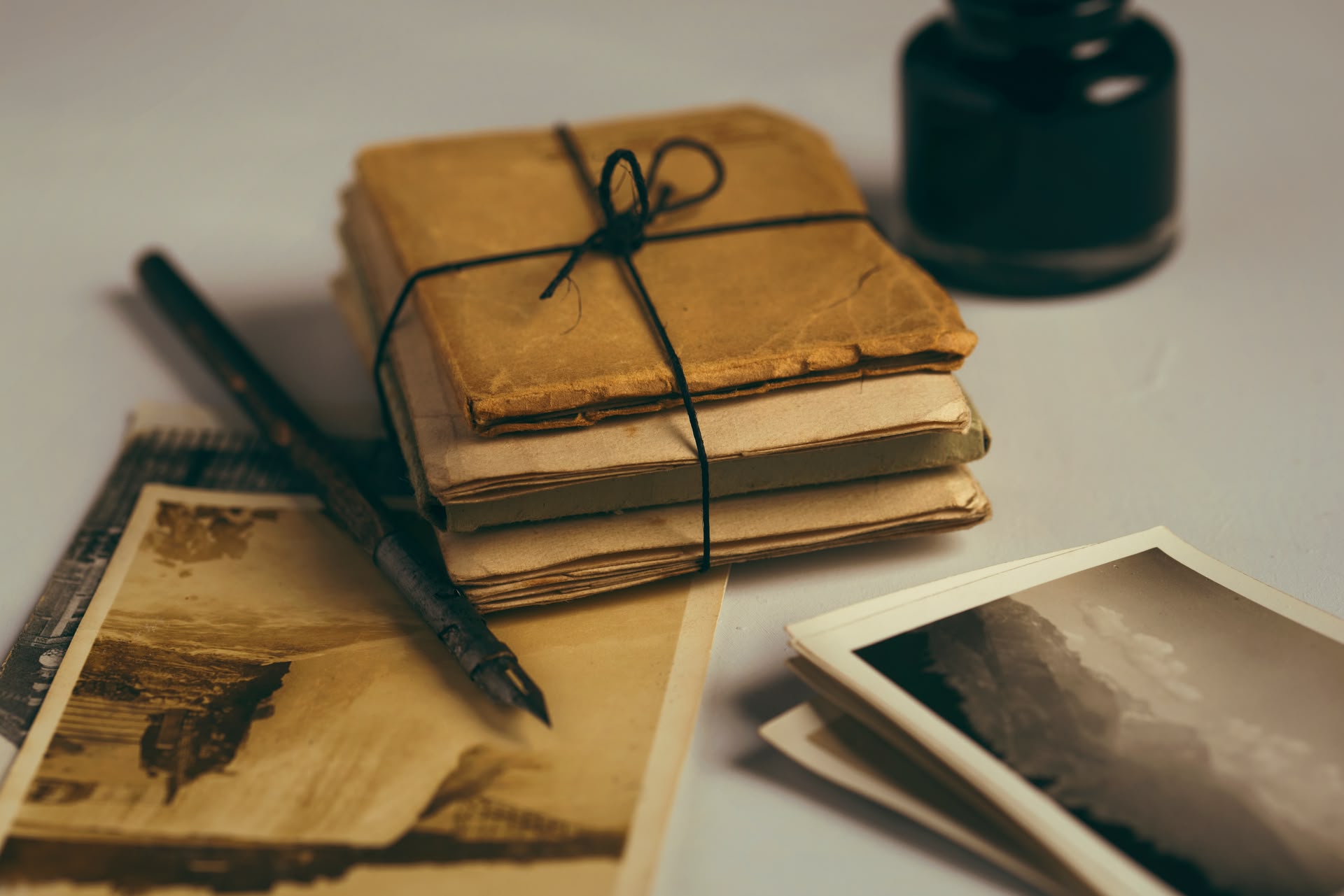 Alte Fotos und zusammengebundene Notizbücher liegen neben einem Füller
