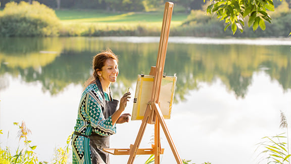 Frau mit Staffelei am See