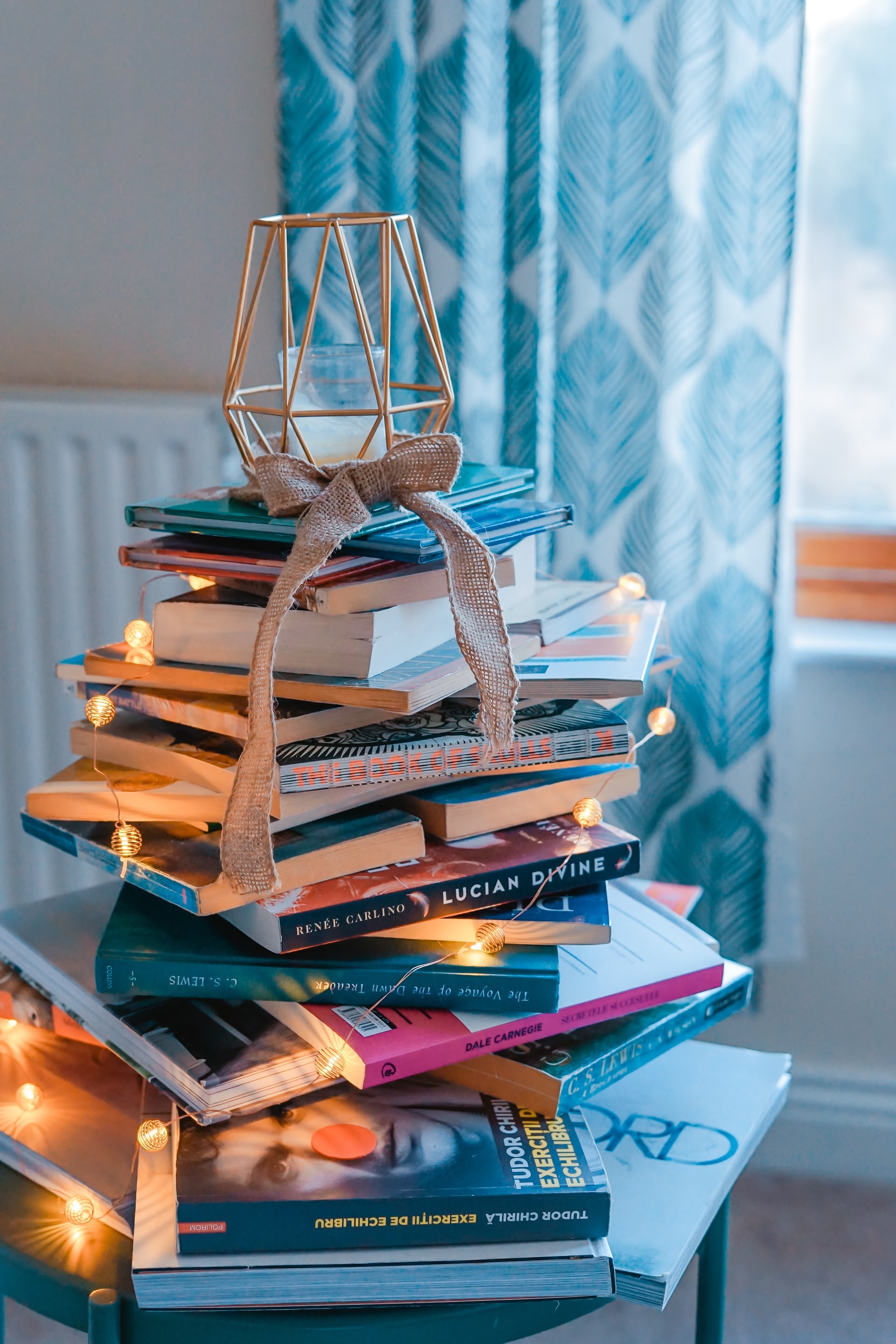Ein Stapel mit Büchern, ganz oben steht eine Kerze darauf