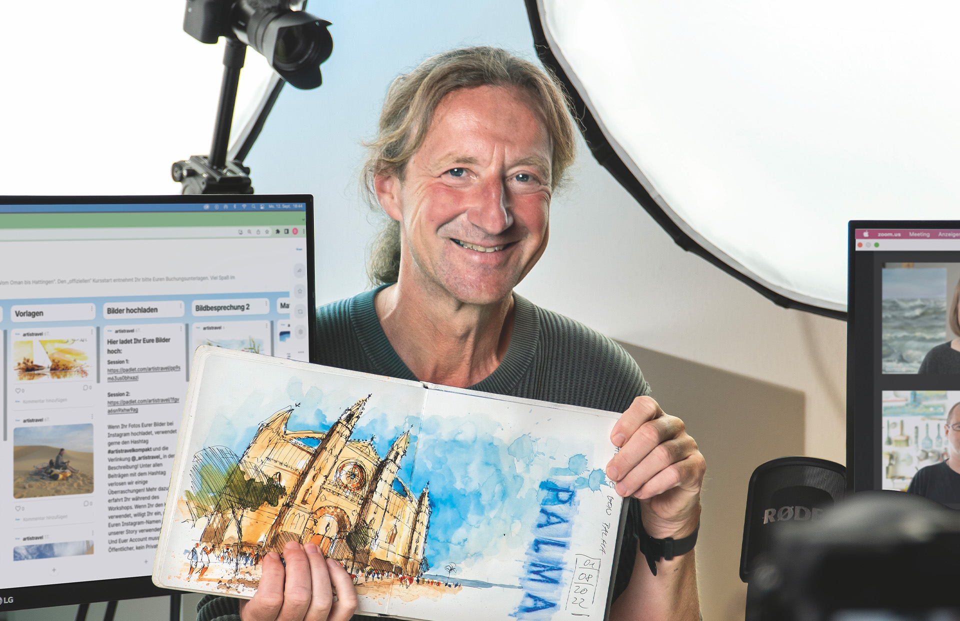 Ein Dozent hält eine Zeichnung hoch, daneben steht ein Computer-Bildschirm